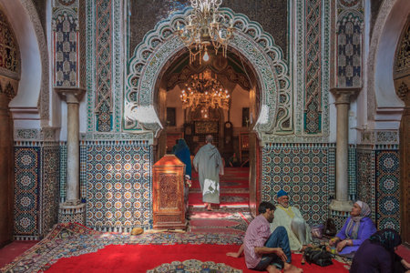 Fes, Morocco - May 11, 2013: People sitting by the entrance to a mosque, decorated with ornate mosaic and arabesque carvingsのeditorial素材