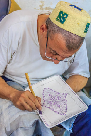 Fes, Morocco - May 11, 2013: Moroccan mozaic paint artist at work in a pottery shopのeditorial素材