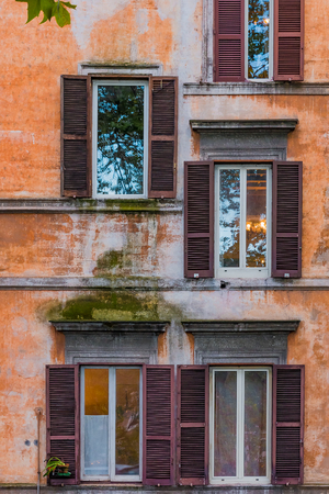 Rows of old windows with shutters on an apartment building in Rome, Italy.の写真素材