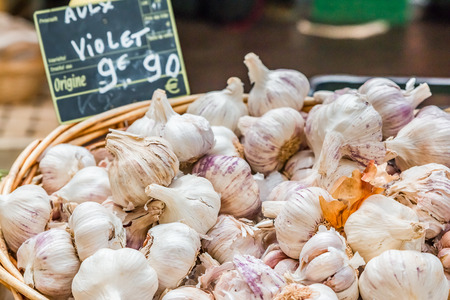 Basket filled with fresh heads of garlic with a handwritten price tag at a local outdoor farmers market in Franceの写真素材