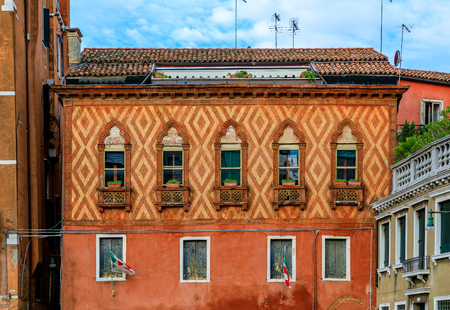 Exterior of a typical old building with shutters and ornate windows with flowers in Venice, Italyの写真素材