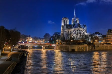 View over the river Seine onto illuminatred back side of Notre Dame de Paris Cathedral at night in, the world famous Gothic Roman Catholic cathedral in Paris, Franceの写真素材