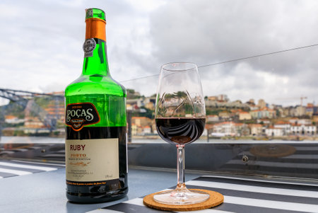 Porto, Portugal - May 30, 2018: Glass and bottle of port wine at an outdoor restaurant with the Douro river and Dom Luis I bridge blurred in the backgroundのeditorial素材