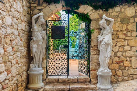 Eze, France - October 14, 2013: Ornate old wrought iron gate and statues in the streets of a picturesque medieval city along the Mediterranean Seaのeditorial素材