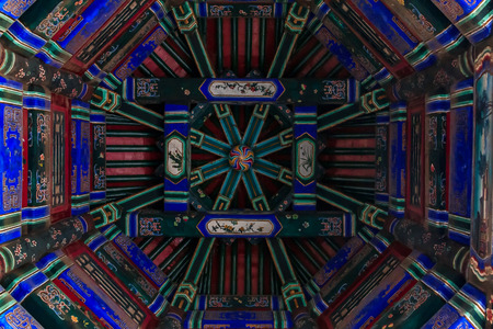 Ornate carved and painted beam and rafters with traditional Chinese designs on the ceiling of a pagoda in Summer Palace, in Beijing, Chinaの写真素材
