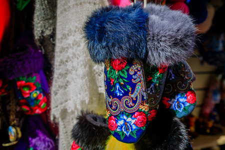 Warm fur trimmed winter gloves with traditional Russian design patters for sale at an open air market in Saint Petersburg, Russia with warm shawls in the backgroundの写真素材