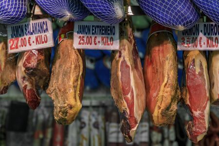 Multiple whole bone-in legs of Spanish serrano iberico ham on display at a butcher shop in a local market Madrid, Spainの写真素材