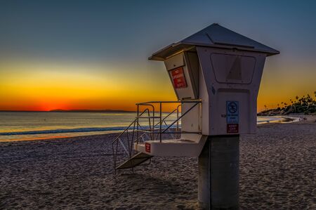 Incredible colors of sunset in Laguna Beach, famous tourist destination in California, USA with a lifeguard station in the foregroundの写真素材