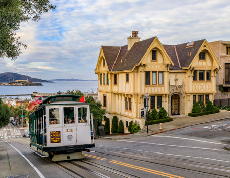 San Francisco, USA - January 21, 2020: The iconic cable car at the top of Hyde Street next to a Tudor house, formerly owned by Nicolas Cage, with the famous Alcatraz Island in backgroundのeditorial素材