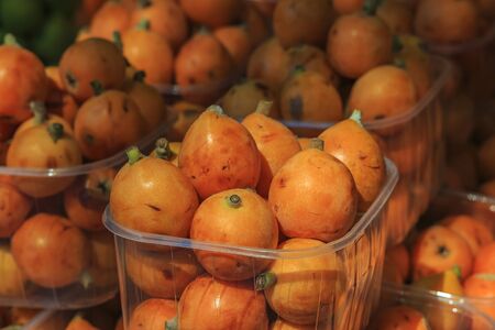 Fresh bright orange loquat medlar fruit in baskets on display at local outdoor farmers market in Ventimiglia, Italyの写真素材