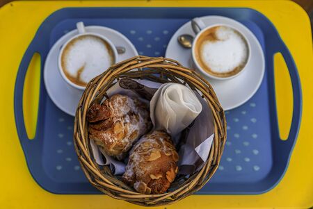 Freshly baked French almond croissants and cups of cappuccino on a platter at breakfast at a bakery cafe in Nice, France, flat lay top down viewの写真素材
