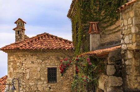 Stone exterior of old buildings with flowers on the streets of Eze Village, picturesque medieval...