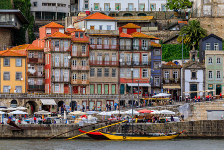 Porto, Portugal - May 30, 2018: Facades of traditional houses with azulejo tile in Ribeira and tourist rabelo boat docked on Douro in Porto Portugalのeditorial素材
