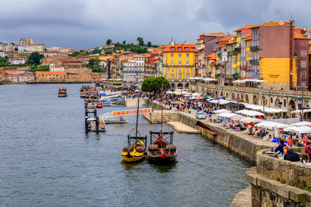 Porto, Portugal - May 30, 2018: Facades of traditional houses with azulejo tile in Ribeira and tourist rabelo boat docked on Douro in Porto Portugalのeditorial素材