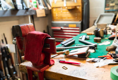 Gunsmithing tools on a working table at a gun shop in California, blurred rifles in the backgroundの写真素材