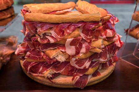 Serrano iberico ham sandwiches or bocadillo held on a wooden platter at a local shop in Pamplona Spainの写真素材