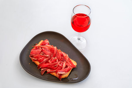 Glass of Spanish rose or rosado and Jamon Iberico tostada or ham and tomato sandwich at a restaurant in the old town or Casco Viejo of Pamplona, Spainの写真素材