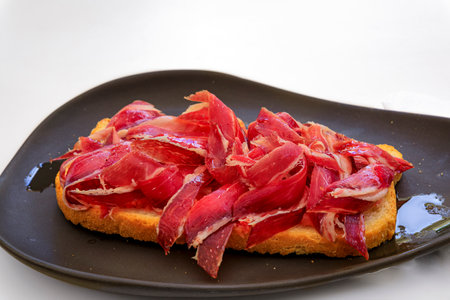 Serrano iberico ham sandwiches or bocadillo held on a wooden platter at a local shop in the old town...
