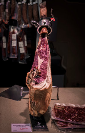 Pamplona, Spain - June 22 2021: Whole bone-in leg of Spanish serrano iberico ham on a carving stand...