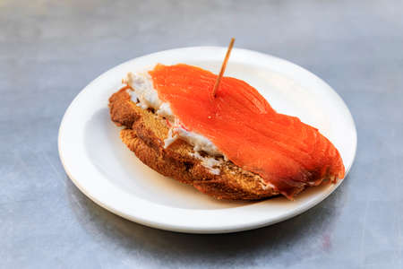 Tostada with smoked salmon and crab salad, pintxos or tapas at an outdoor restaurant in Olite, Spain