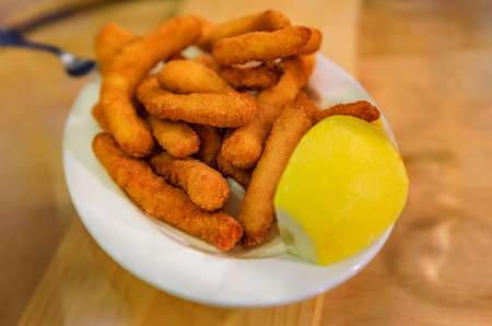 A plate of traditional Spanish pintxos or tapas of fried calamari with lemon in a restaurant, San Sebastian Donostia, Basque Country, Spainの写真素材