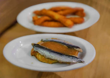 Spanish pintxos or tapas of anchovies on foie gras with apple compote and fried calamari in a restaurant, San Sebastian Donostia, Basque Country Spainの写真素材