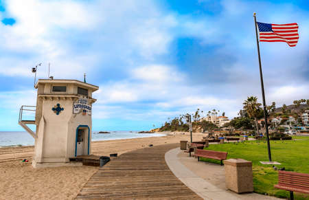 Lifeguard station and an American flag in Laguna Beach, famous tourist destination in California, Pacific Ocean in the background a on a cloudy dayの写真素材