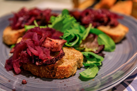 Freshly made bruschetta with grilled octopus and pickled onions at a restaurant in old town of Manarola in Cinque Terre on Mediterranean Sea, Italyの写真素材