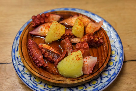 Traditional Basque pintxos octopus with potatoes and paprika in olive oil on a wooden platter in a bar, San Sebastian Donostia, Basque Country, Spainの写真素材