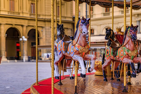 Ornate antique carousel with wooden horses on Piazza della Republica during the day in Florence,...