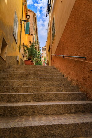 Stairs on a narrow street between traditional old terracotta houses in the Old Town of Villefranche sur Mer on the French Riviera, South of Franceの写真素材