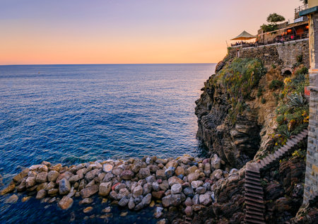 Sunset view onto the Mediterranean Sea with cliffs above the water in old town of Riomaggiore in Cinque Terre, Italyの写真素材
