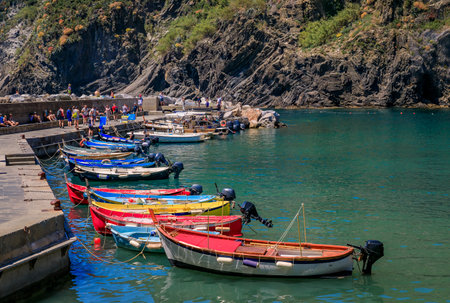 Traditional colorful fishing boats docked at a pier on the Mediterranean Sea in Cinque Terre, Vernazza, Italyの写真素材