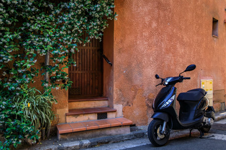 Scooter leaning against a traditional old house by the local covered provencal farmers market in the old town or Vieil Antibes, South of Franceの写真素材