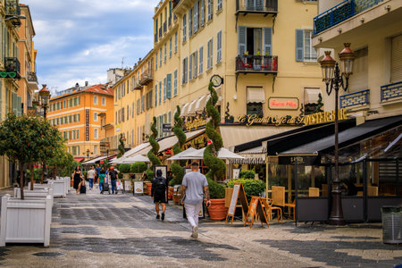 Nice, France - May 29, 2023: People walk by restaurants and bars on a busy pedestrian street in the Old Town, Vieille Ville, French Rivieraのeditorial素材