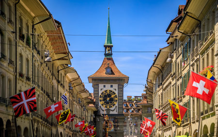 The Zytglogge clock tower with an ornate astronomical clock in the medieval Altstadt, Old City of Bern, Switzerland, flags on surrounding buildingsの写真素材