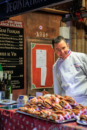 Strasbourg, France - December 13, 2024: Famous Chef Gilles Reinhardt of Paul Bocuse restaurant serves foie gras sandwiches at the Chrismas Marketのeditorial素材