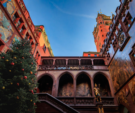 Christmas tree with colorful ornaments stands in the courtyard of Rathaus des Kantons Basel Stadt townhall in Basel, Switzerland, murals on the wallsの写真素材