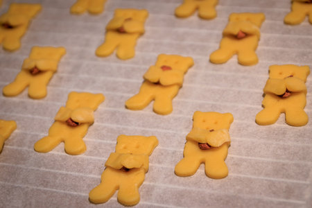 Adorable bear shaped homemade sugar cookies holding an almond in its paws on a baking sheet, ready for the oven, Christmas time holiday bakingの写真素材