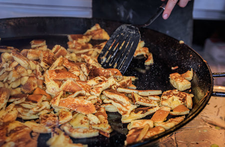 Vendor cooks a golden brown Kaiserschmarrn, a traditional Austrian pancake dish, sizzling in a pan at the Zurich Christmas Market, Switzerlandの写真素材