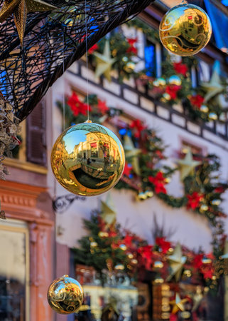 Close-up of shimmering gold Christmas ornaments against a backdrop of festive decorations on a building facade at the Colmar Christmas Market, Franceの写真素材