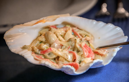 Creamy seafood salad with imitation crab and artichoke hearts served in a decorative scallop seashell at a restaurant in Istanbul, Turkeyの写真素材