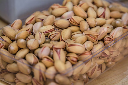 Fresh whole pistachios in shells on display in a clear box for sale in bulk at a vibrant bazaar...