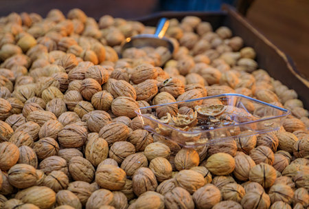 Fresh whole walnuts in shells on display in a box with a metal scoop for sale in bulk at a vibrant...