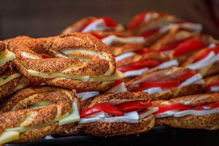 Stacked traditional simit sandwiches with cheese and tomato prepared for breakfast at a bustling...