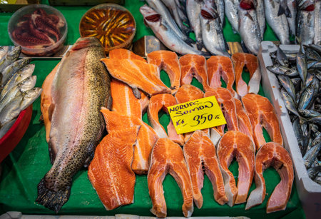 Selection of freshly cut Norwegian salmon filets and a whole fish on display for sale with a price...