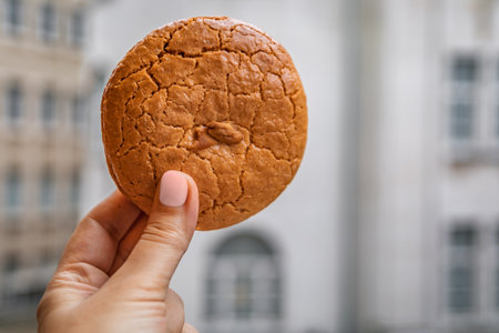 A woman s hand holds a traditional almond cookie with a background of Ottoman baroque city...