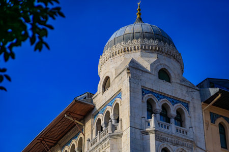 The ornate facade of a historic building with an Ottoman style dome, intricate arches and mosaic tile work against a clear blue sky, Istanbul, Turkeyの写真素材