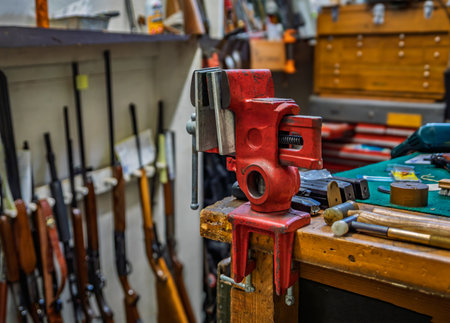 Gunsmithing tools on a working table at a gun shop in California, blurred rifles in the backgroundの写真素材