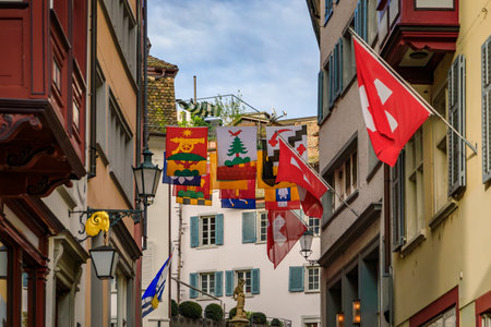 Swiss flags hang from the historic facades of traditional buildings in the Old Town Aldstadt on the famous Augustinergasse street, Zurich, Switzerlandの写真素材